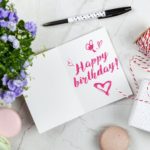 happy birthday card beside flower thread box and macaroons