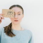 a woman holding a cardboard with an eye drawing